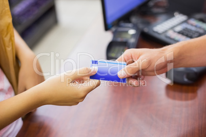 Smiling woman at cash register paying with credit card