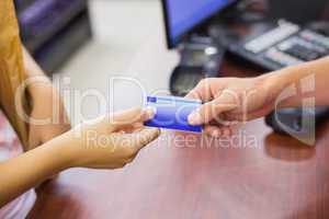 Smiling woman at cash register paying with credit card