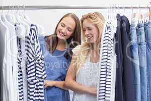 Happy friends browsing in the clothes rack