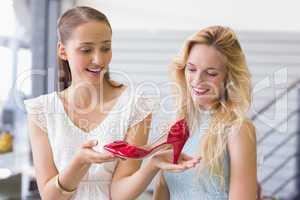 Happy women looking at a heel shoe