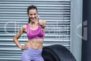 Smiling muscular woman gesturing thumbs up