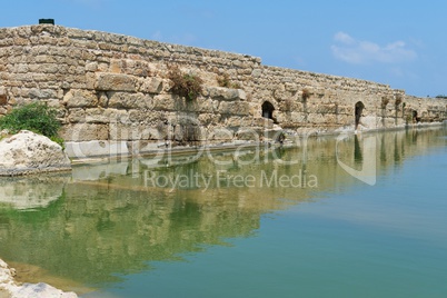 Ancient wall reflecting in the pond in Nahal Taninim archeological park in Israel