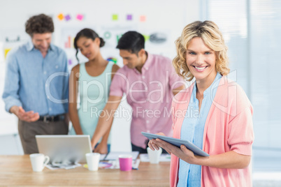 Casual businesswoman using digital tablet with colleagues behin
