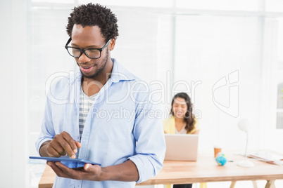 Man posing in front of his colleague with tablet computer