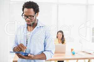 Man posing in front of his colleague with tablet computer