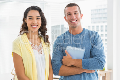 Portrait of smiling colleagues with tablet computer looking at c