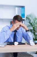 Businessman with severe headache sitting at office desk