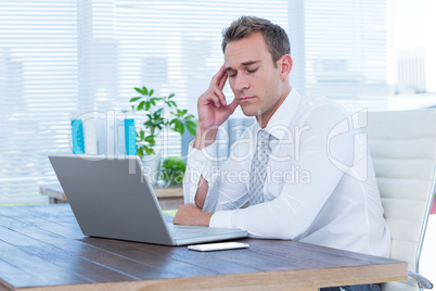 Exhausted businessman drowsing on his laptop