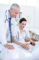 Smiling medical colleagues working with laptop