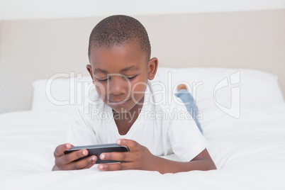 Pretty little boy using smartphone in bed