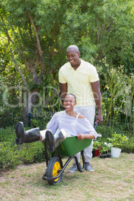 Happy smiling couple playing with wheelbarrow