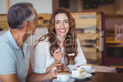 Casual couple having coffee and cake together