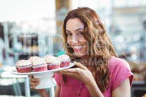 Pretty brunette holding plate of pastries