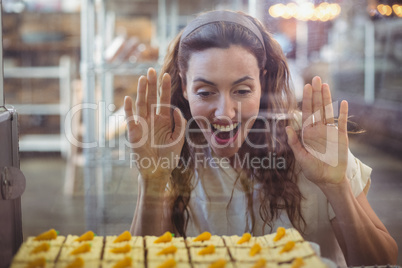 Pretty brunette looking at pastries through the glass