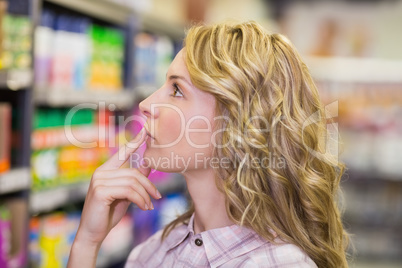 Side view on pretty blonde woman looking at shelf