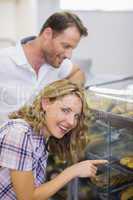 Portrait of a smiling blonde woman looking at pastry