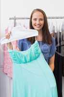 Happy brunette showing a blue dress