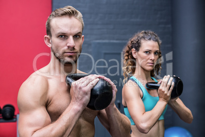 Muscular couple exercising with kettlebells