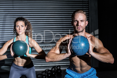 Muscular couple doing ball exercise