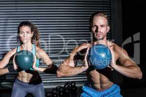 Muscular couple doing ball exercise