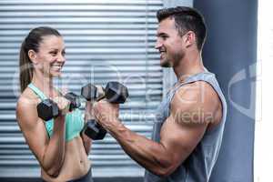 A muscular couple lifting dumbbells