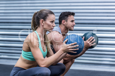 Muscular couple doing ball exercise