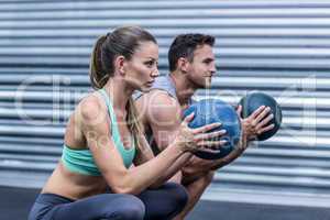 Muscular couple doing ball exercise