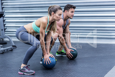 Muscular couple doing ball exercise