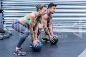 Muscular couple doing ball exercise