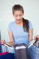 Young surprised woman looking at her shopping bags