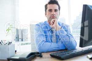 Businessman sitting on an office chair with hand on chin