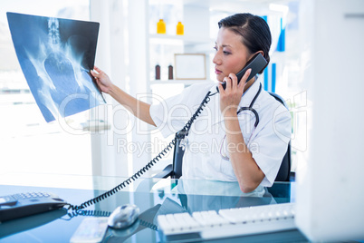 Doctor looking X-rays while having phone call