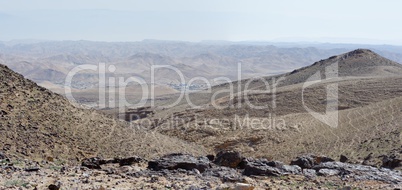 Desert landscape with far Bedouin camp on hazy day