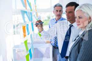 Businessman writing on post it with his colleagues