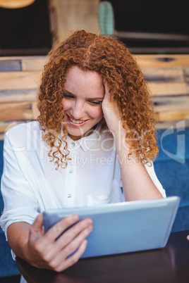 Pretty girl using a small tablet at table