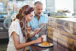 Pretty brunette using her smartphone with coffee in her hand