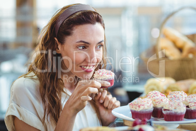 Pretty brunette holding and smelling cupcake