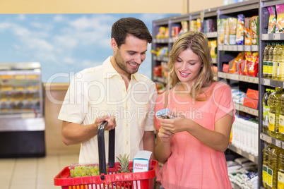 Smiling bright couple buying food products with shopping basket
