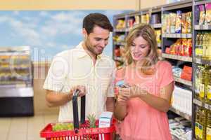 Smiling bright couple buying food products with shopping basket