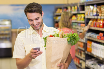 Smiling handsome man buying food products and using his smartpho