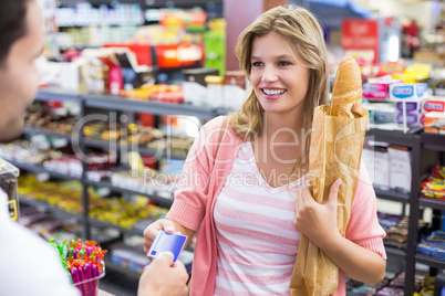 Smiling woman at cash register paying with credit card