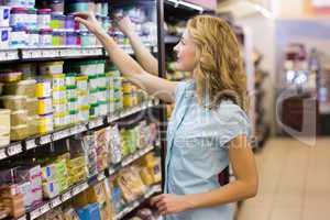 Pretty blonde woman taking a products in shelves