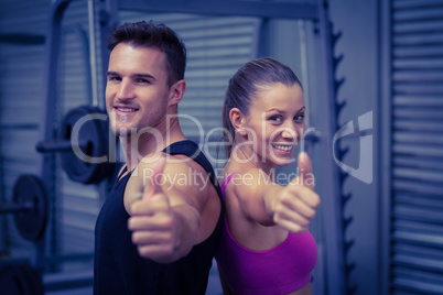 Smiling muscular couple gesturing thumbs up