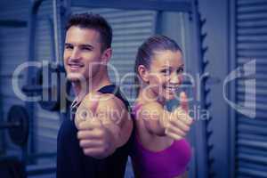 Smiling muscular couple gesturing thumbs up