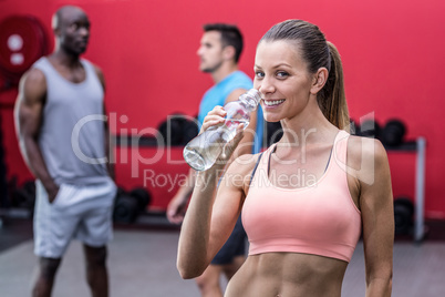 Smiling muscular woman drinking water