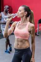 A muscular woman drinking a water