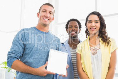 Portrait of smiling colleagues presenting tablet computer and lo