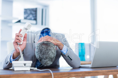 Depressed businessman holding phone