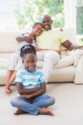 Portrait of a happy couple sitting on couh and their daughter si