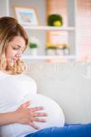 Pregnant woman touching her belly on the couch